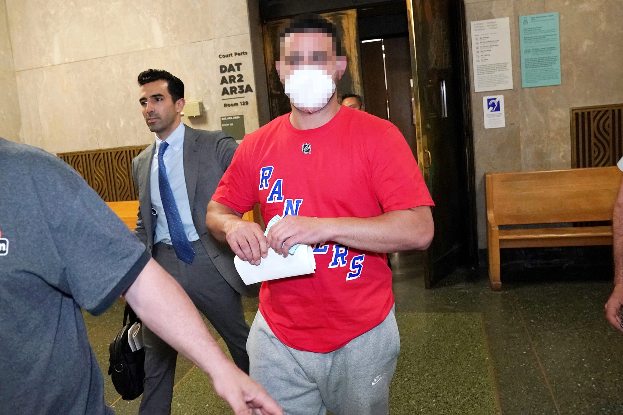 Criminal defense attorney accompanies a client through a New York City courthouse hallway.